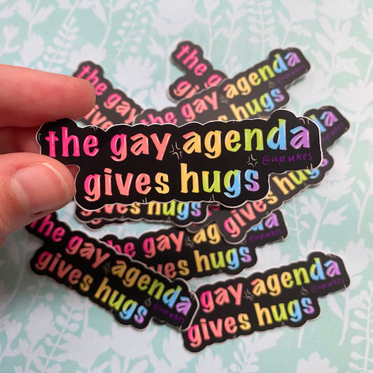 The Gay Agenda Gives Hugs Sticker, 3”x1”